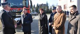 Zaproszeni goście gratulują prezesowi OSP Bałtów nowego pojazdu. W tle samochód gaśniczy i plac KP PSP w Ostrowcu Św.