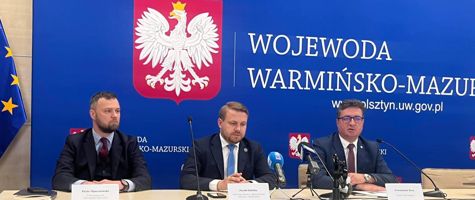 Przy stole w siedzibie Urzędu Wojewódzkiego w trakcie konferencji prasowej siedzą Wiceminister klimatu i środowiska, Wicewojewoda Warmińsko-Mazurski oraz Prezes Wód Polskich