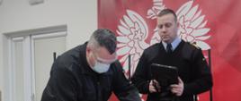 Druh Ochotnik OSP podczas egzaminu potwierdzającego tytuł ratownika wykonuje czynności na fantomie niemowlaka pod okiem egzaminatora