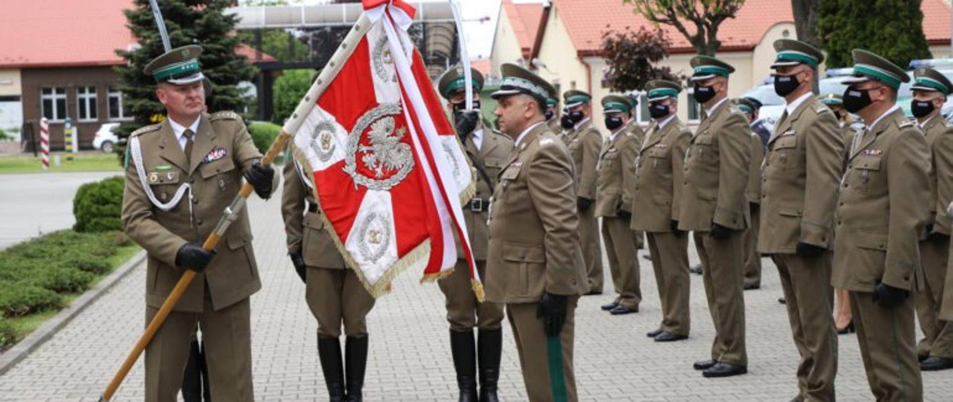 Funkcjonariusze Bieszczadzkiego Oddziału Straży Granicznej i komendant Bieszczadzkiego Oddziału Straży Granicznej na tle sztandaru