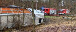 przewrócona ciężarówka, w tle dwa samochody pożarnicze