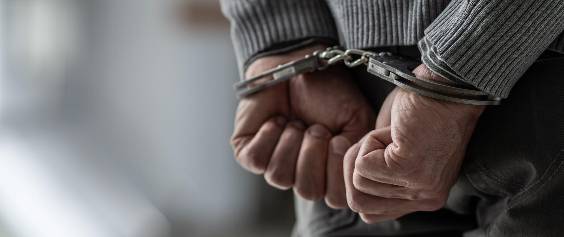 Dłonie mężczyzny skute w kajdanki