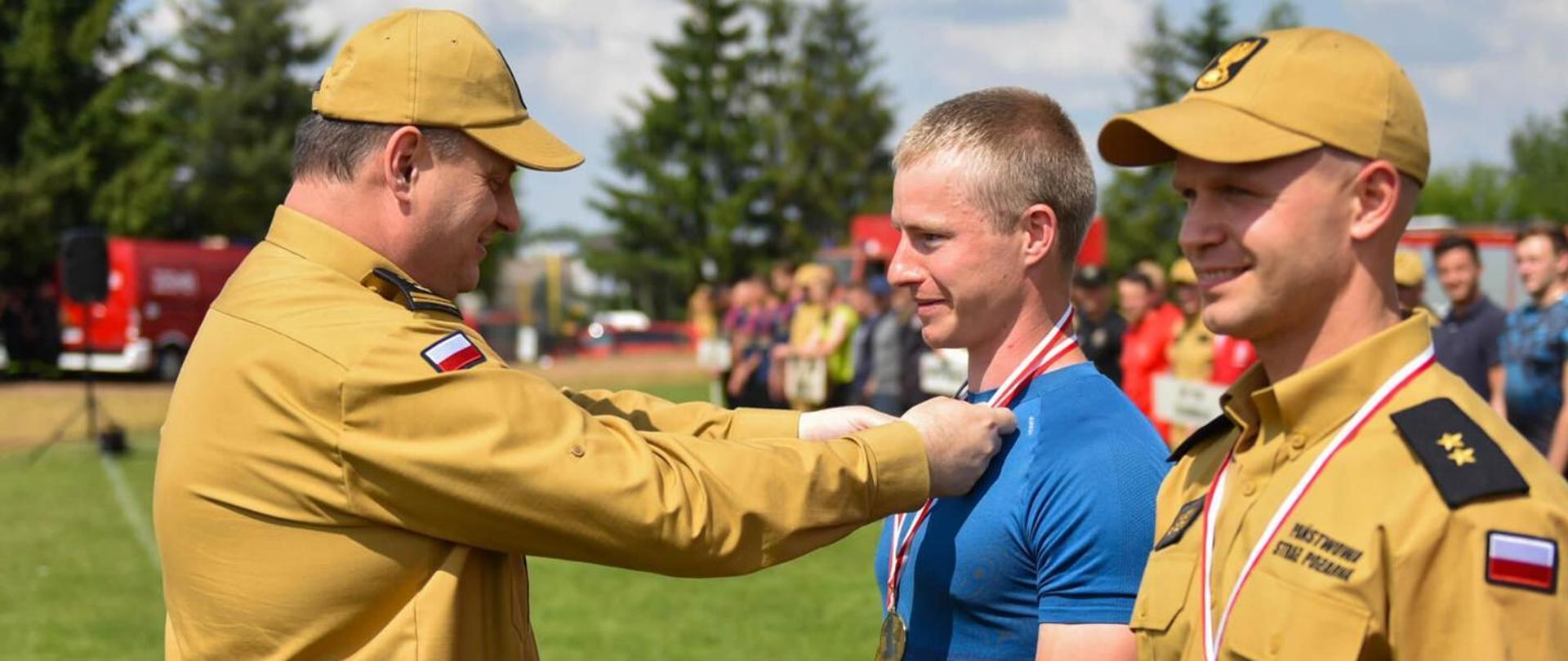 komendant wojewódzki PSP w Łodzi wręczający medal zawodnikowi