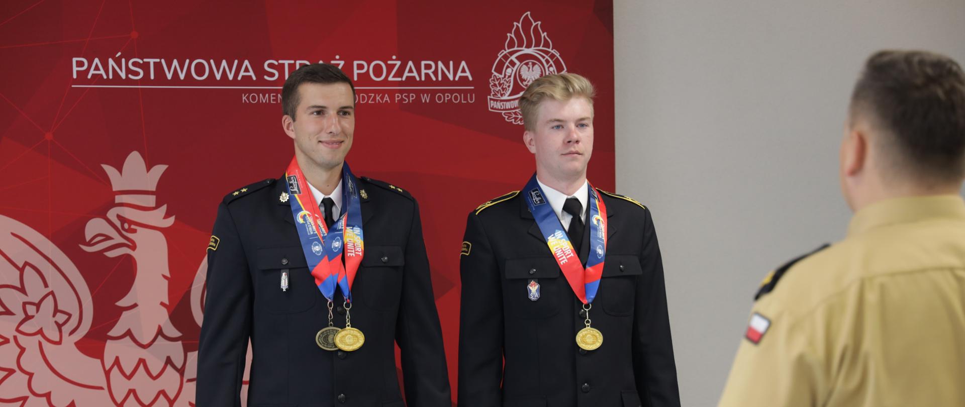 Zdjęcie przedstawia mł. kpt. Jakuba Korczyka oraz asp. Oskara Ułamka podczas uroczystości wyróżnienia nagrodą Opolskiego Komendanta Wojewódzkiego