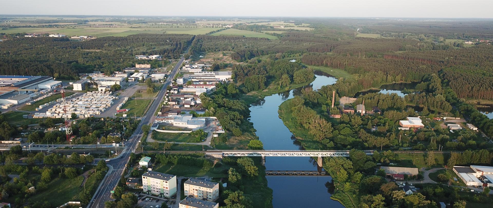Zdjęcie przedstawia Oborniki i biegnącą przez miejscowość drogę krajową nr 11. Widoczne zabudowania wielorodzinne. W centralnej części zdjęcia rzeka Warta.