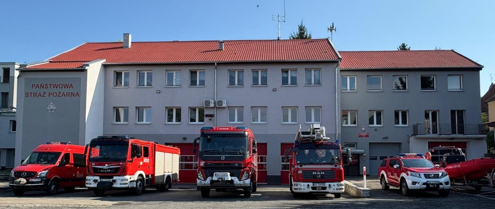 Widoczna od frontu jednostka ratowniczo gaśnicza nr 2 w Elblągu. Przed bramami garażowymi stoją wystawione pojazdy pożarnicze.