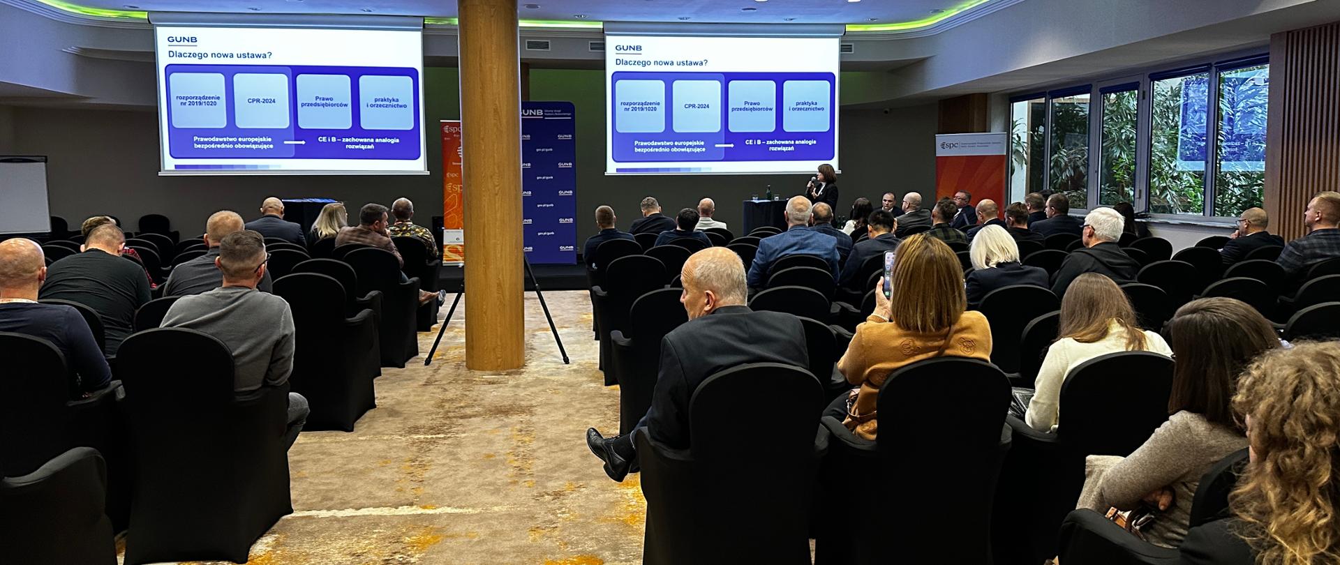 Sala konferencyjna, uczestnicy i prelegent Iwona Tokarska dyrektor Departamentu Wyrobów Budowlanych w GUNB