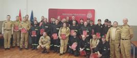Na zdjęciu uczestnicy szkolenia kierowców-konserwatorów sprzętu ratowniczego OSP, który odbył się w Komendzie Powiatowej PSP w Pabianicach. Zdjęcie wykonane po uroczystym wręczeniu zaświadczeń potwierdzających zdanie egzaminu. Kursanci stoją na tle ścianki z logiem PSP.