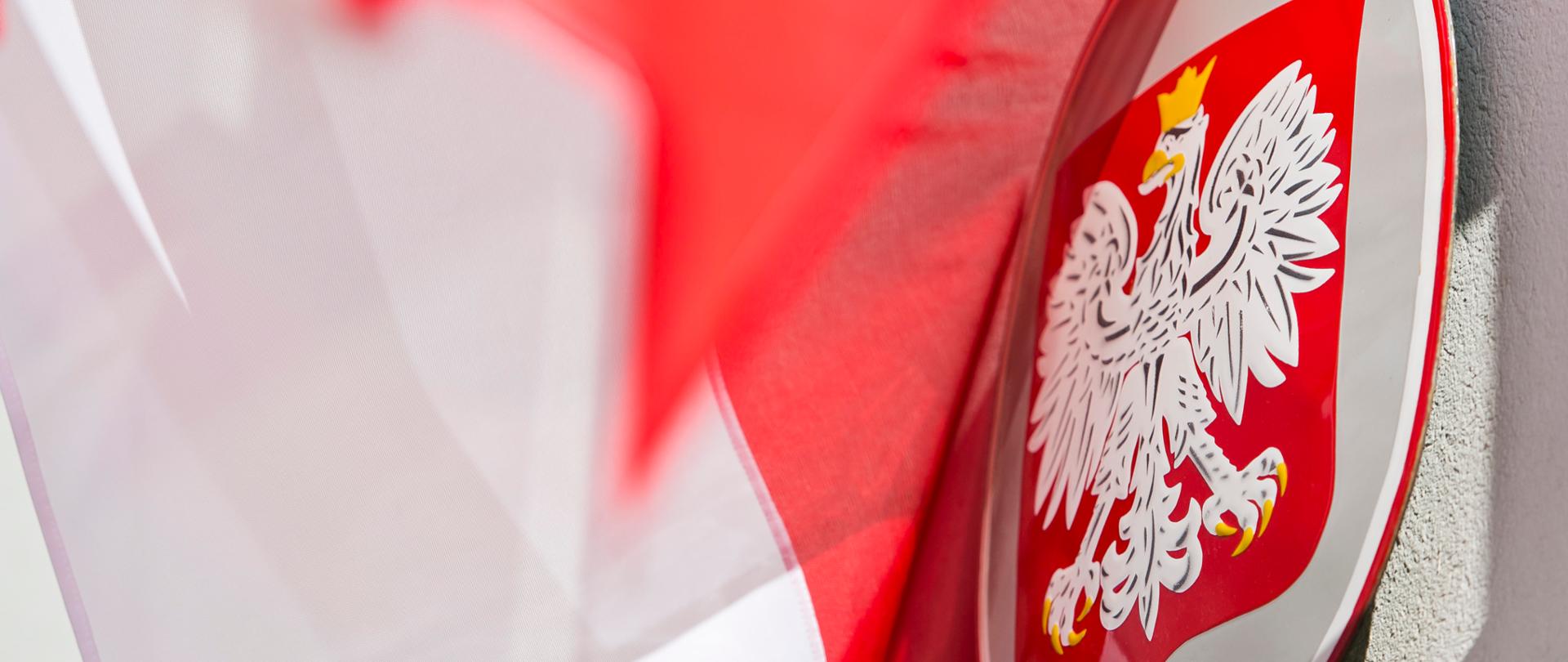 Zdjęcie przedstawiające Godło Rzeczypospolitej Polskiej, orła białego ze złotą koroną na głowie zwróconej w prawo oraz flagę biało-czerwoną