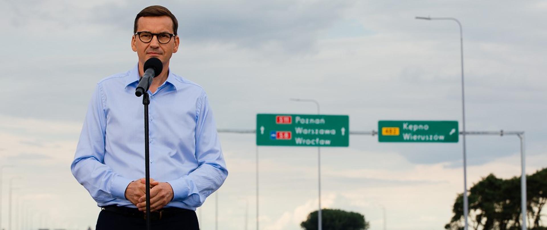 Premier przemawia na tle drogi.