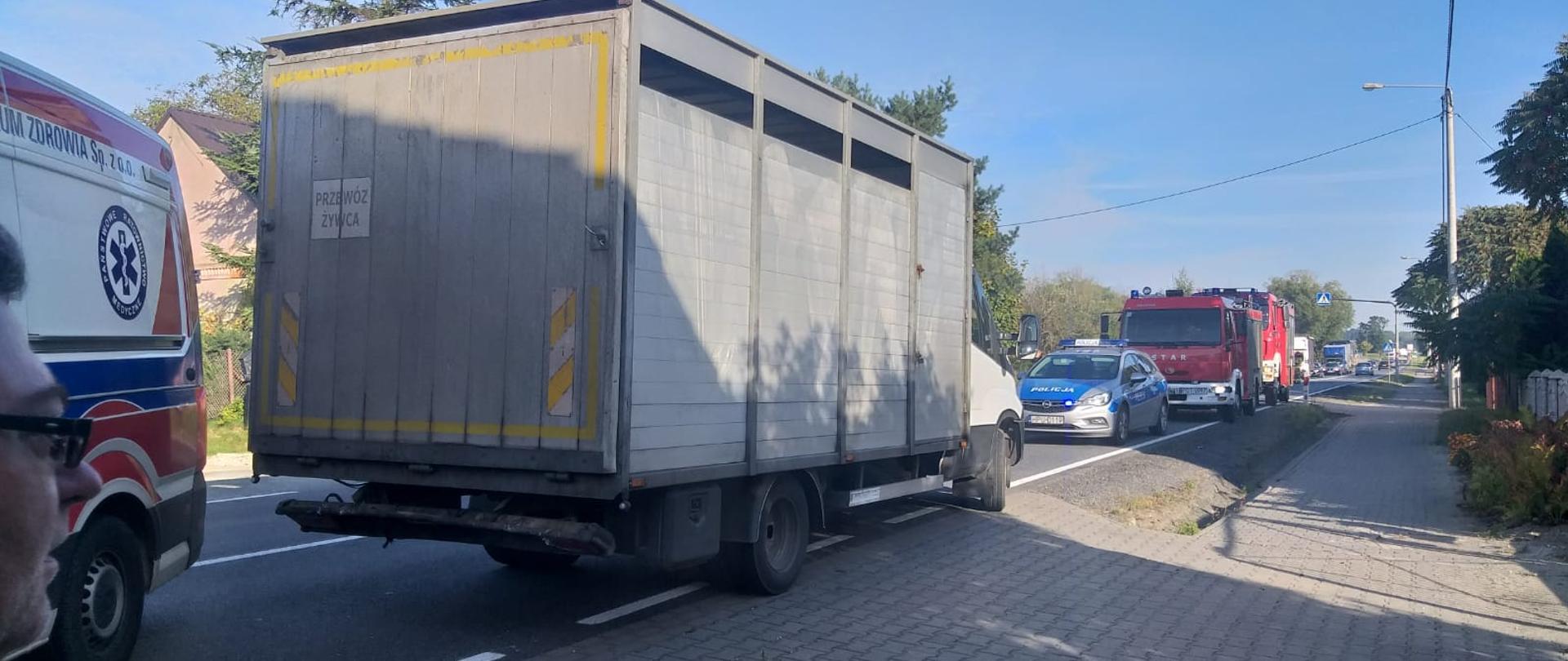 Zdjęcie przedstawia kolizję 3 pojazdów na drodze krajowej nr 11 w miejscowości Turze. Na zdęciu widzimy uszkodzony samochód dostawczy oraz pojazdy ratownicze biorące udział w działaniach. Zdjęcie wykonane w porze dziennej na drodze.