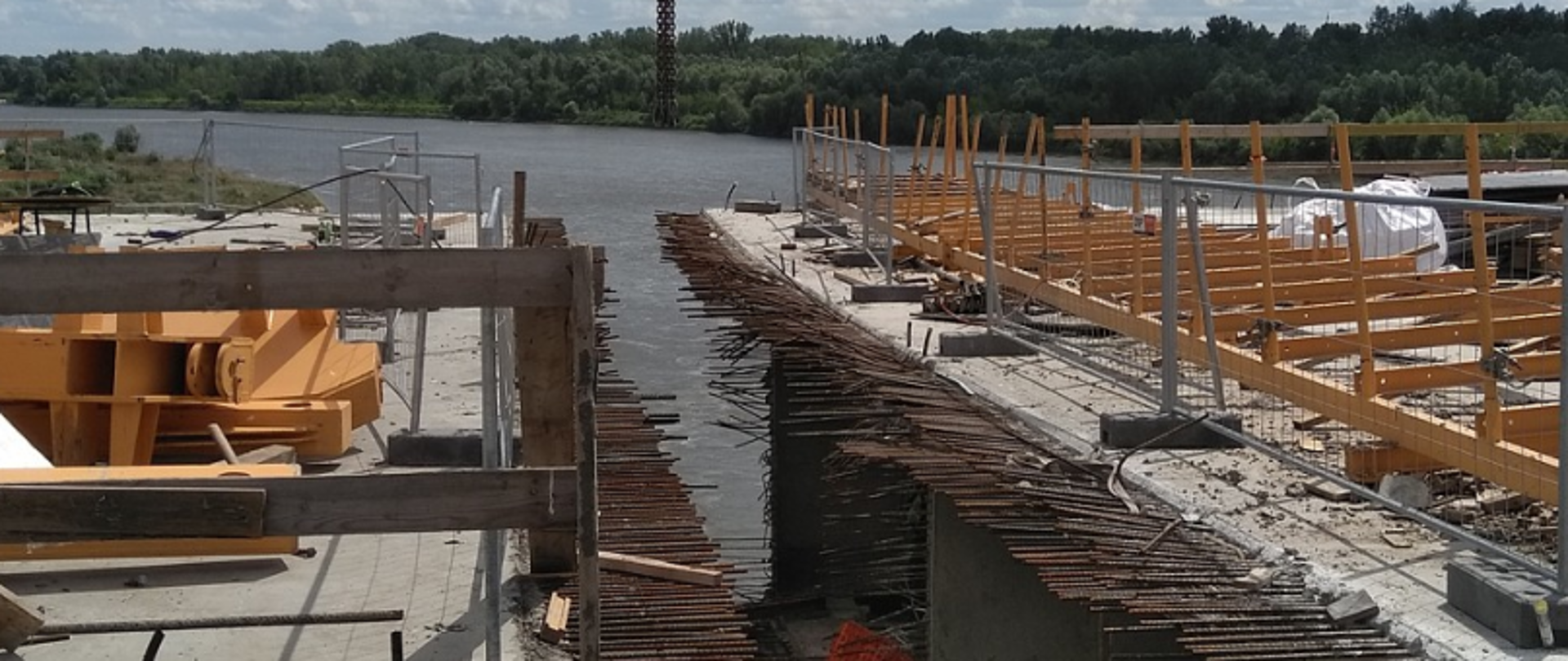 Plac budowy nad rzeką z materiałami i sprzętem budowlanym