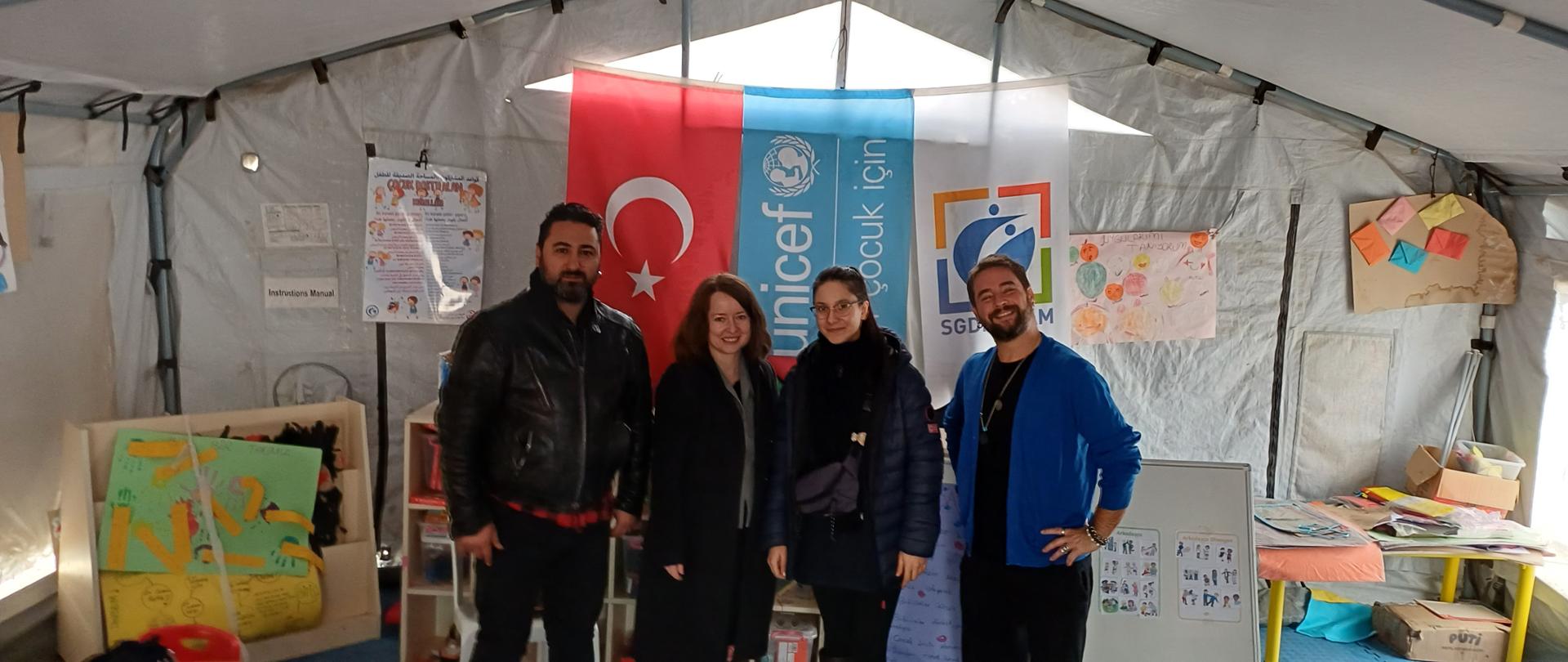 Two men and two women are posing to the photo in a tent
