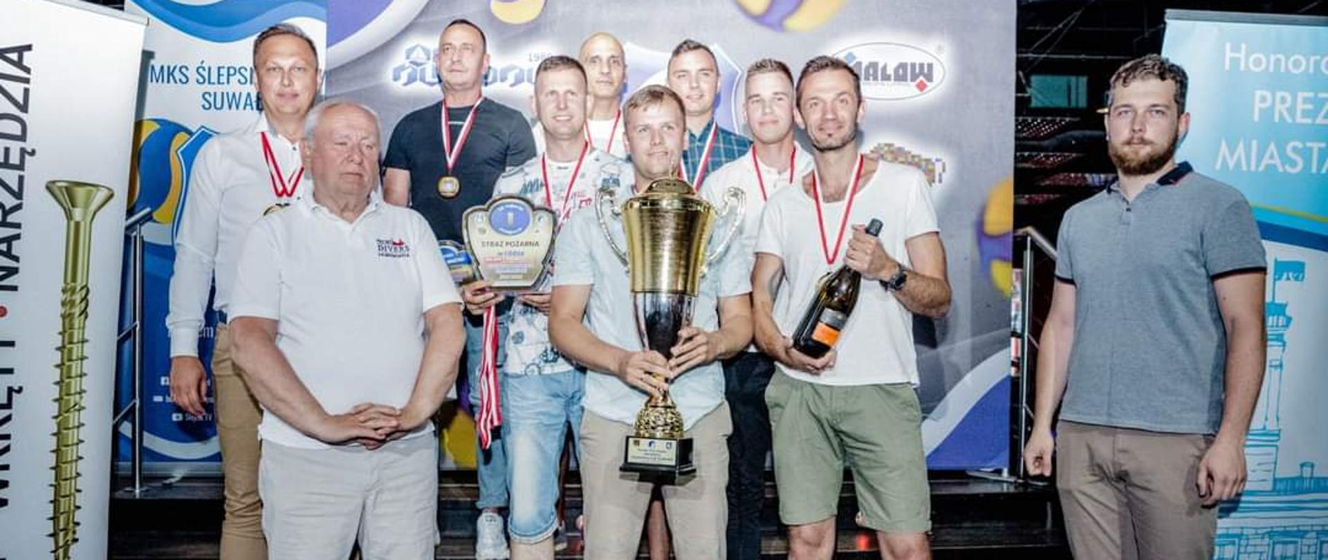 Zawodnicy z organizatorami i sponsorami na tle po wręczeniu medali i pucharu. 