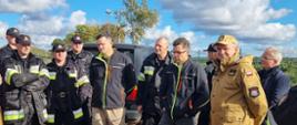 Strażacy słuchają przedstawicieli farmy fotowoltaicznej stoją obok nich.