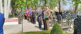Na cmentarzu stoją poczty sztandarowe widoczni również żołnierze oraz osoby cywilne