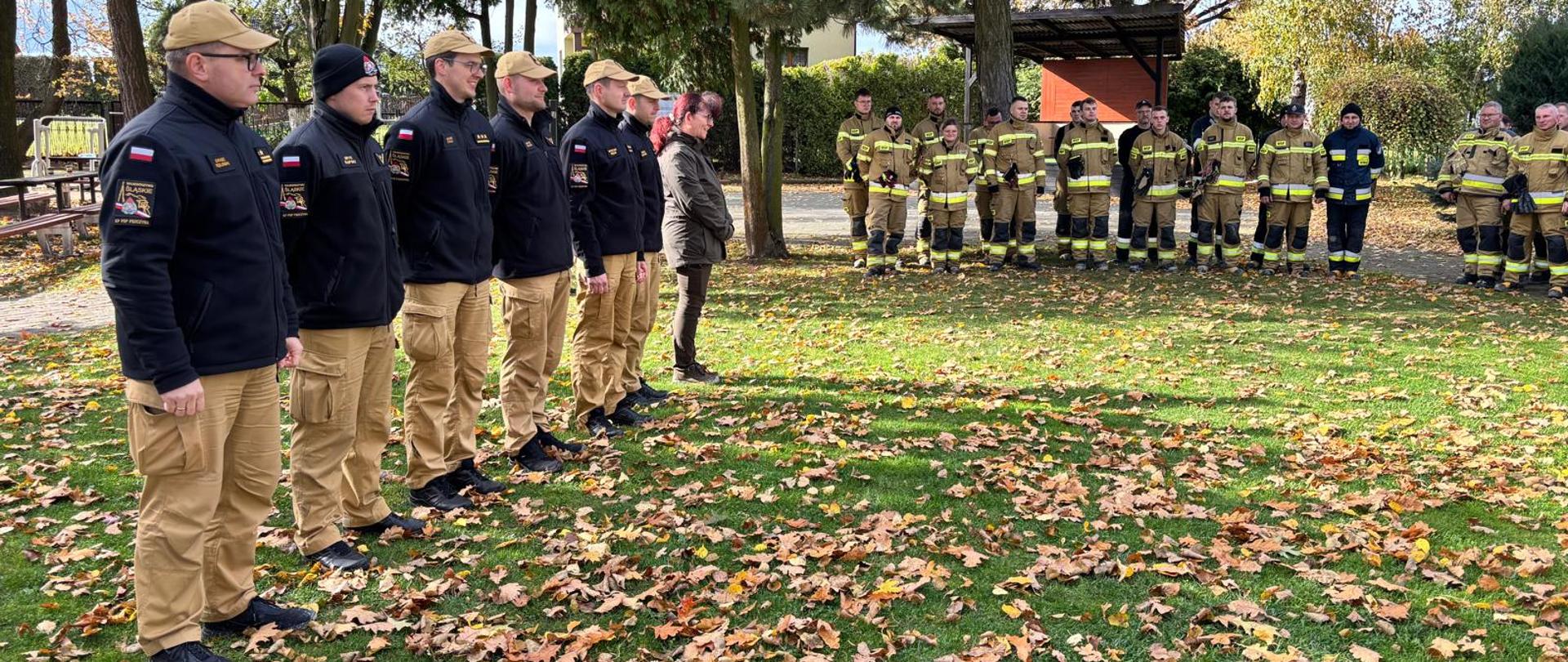 Strażacy PSP i OSP waz z zaproszonymi gośćmi na terenie zielonym podczas zbiórki