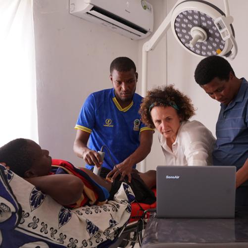 Lekarka pokazuje jak wykonać badanie na leżącym pacjencie, wykonywane jest usg, 4 osoby obserwują jej pracę