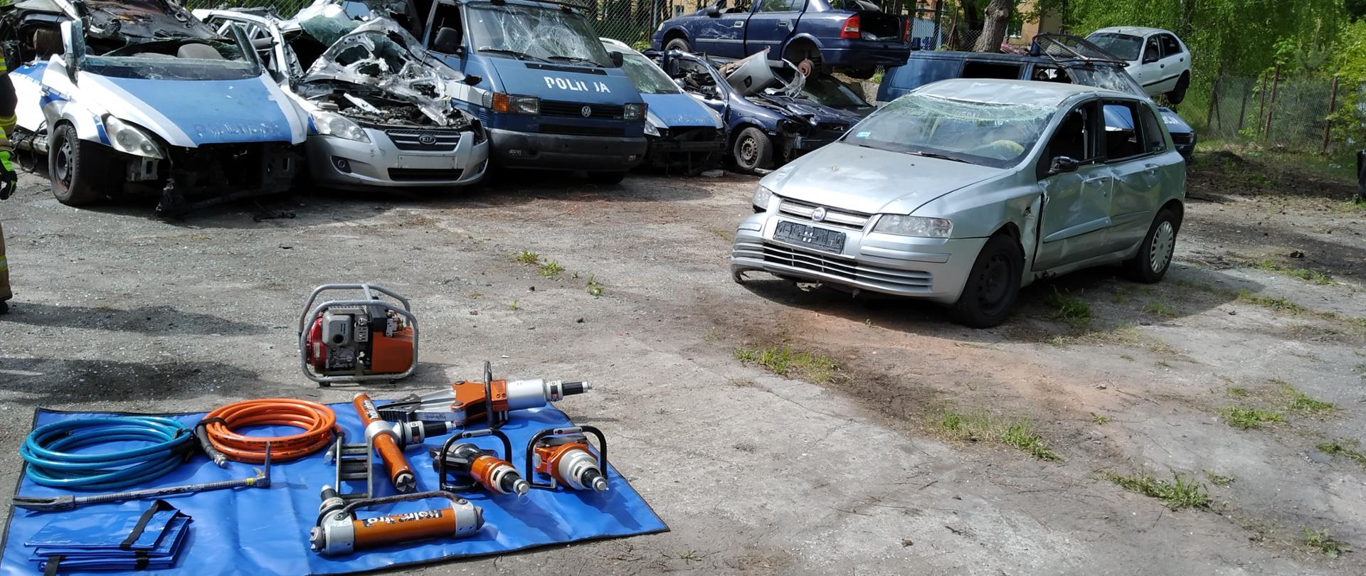 Ćwiczenia z zakresu ratownictwa technicznego realizowane na terenie CSP w Legionowie. Mata ze sprzętem hydraulicznym oraz samochód przeznaczony do ćwiczeń.