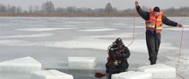 Dwóch strażaków przygotowujących się do nurkowania pod lodem w ramach ćwiczeń doskonalących.
