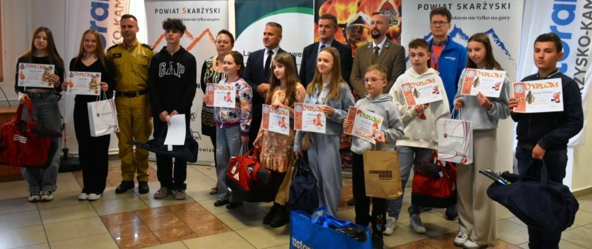 Zdjęcie obrazuje laureatów eliminacji powiatowych Ogólnopolskiego Turnieju Wiedzy Pożarniczej. W ręku trzymają oni dyplomy i nagrody jakie otrzymali.