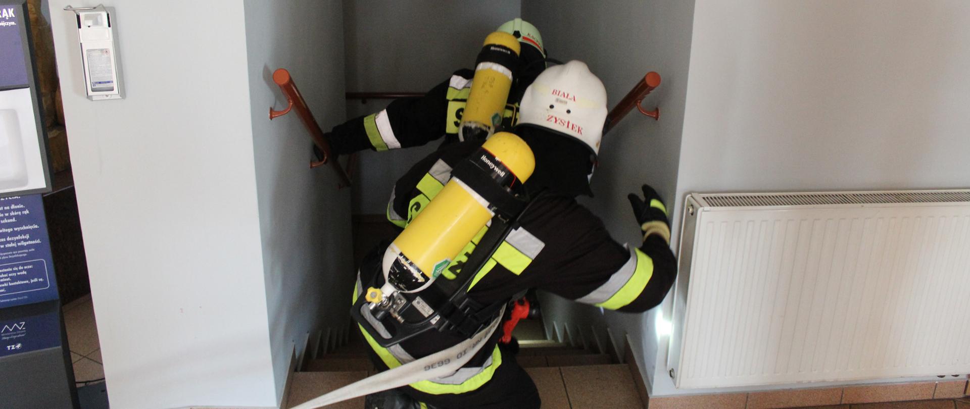 Strażacy wchodzą do klatki schodowej 