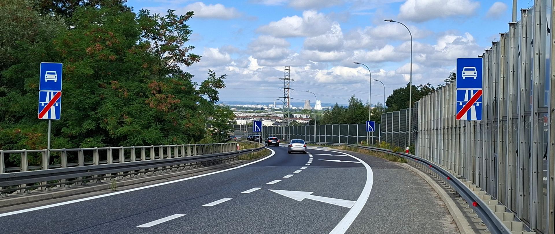 Węzeł Bieżanów, łącznica z A4 na S7, dwa pasy łącznicy, prawy pas zanikający, w oddali zabudowania Krakowa i kominy elektrociepłowni
