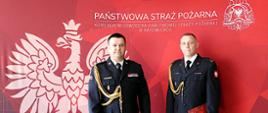 Na zdjęciu ścianka w kolorze czerwonym z godłem Polski, po lewej stronie, u góry napis Państwowa Straż Pożarna Komenda Wojewódzka Państwowej Straży Pożarnej w Katowicach. W prawym górnym rogu logo Państwowej Straży Pożarnej. Na tle ścianki stoją w mundurach wyjściowych: po lewej Śląski Komendant Wojewódzki PSP nadbryg. Jacek Kleszczewski a po prawej stronie nowo powołany Zastępca Komendanta Miejskiego mł. bryg. Tomasz Starowicz.