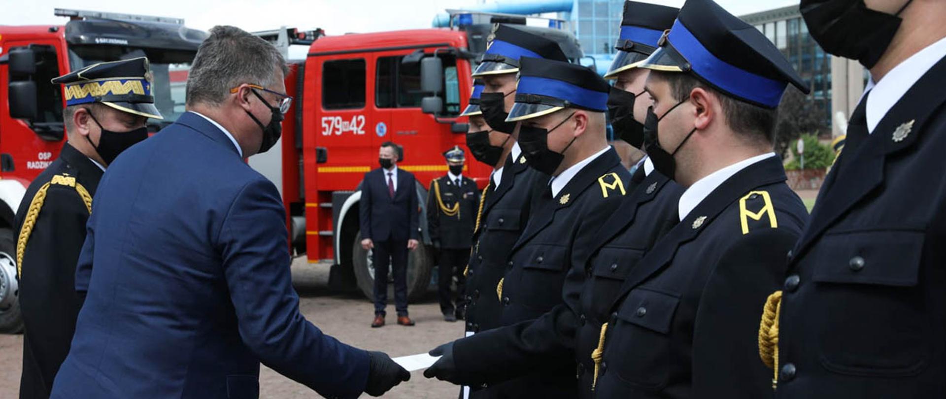 Wiceminister Maciej Wąsik wręczający akty nadania awansów na wyższe stopnie służbowe strażakom Państwowej Straży Pożarnej.