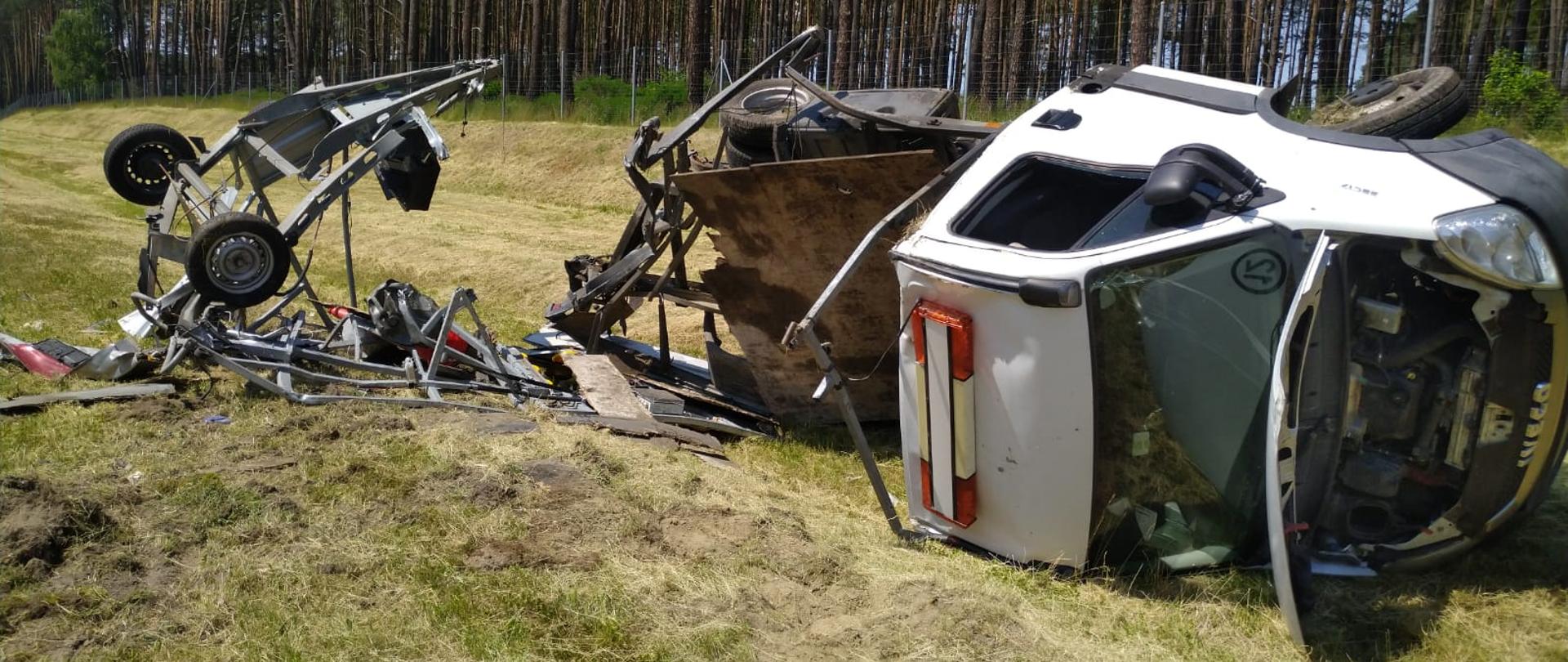 Zdjęcie przedstawia rozbity pojazd IVECO DAILY należący do obsługi autostrady A-2 leżący na boku poza pasem autostrady na skutek wcześniejszego zderzenia z pojazdem ciężarowym marki DAF z naczepą. 
