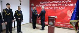 Komendanta Powiatowy PSP Łukasz Szopa wręcza decyzje o zwolnieniu ze służby st. ogn. Łukaszowi Nogieciowi