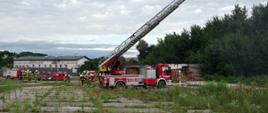 Widok z boku. Miejsce ćwiczeń. Po prawej stronie samochód-drabina. Na placu trzy zastępy ratownicze. 