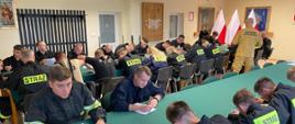 widoczni strażacy w trakcie rozwiązywania testu, w tle sala szkoleniowa