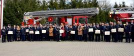 Na zdjęciu na tle samochodów pożarniczych przedstawiciele OSP oraz zaproszeni goście z wręczonymi podczas uroczystego apelu promesami.