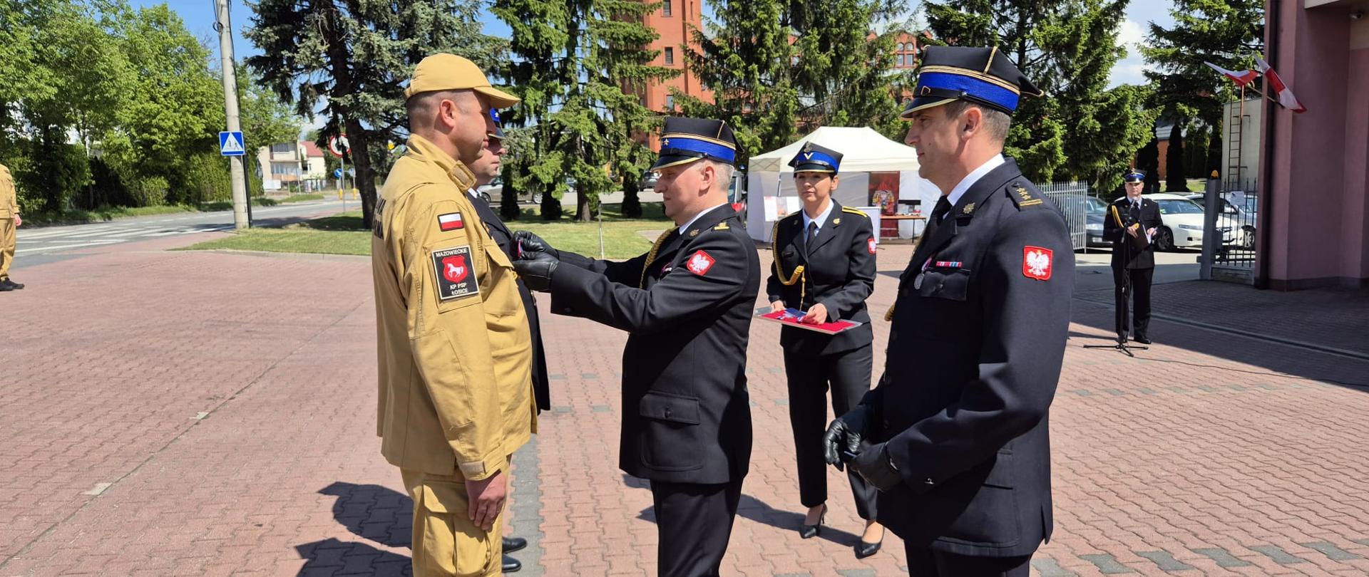 Podczas Powiatowych Obchodów Dnia Strażaka w Łosicach Zastępca Mazowieckiego Komendanta Wojewódzkiego Państwowej Straży Pożarnej wręcza odznaczenie.