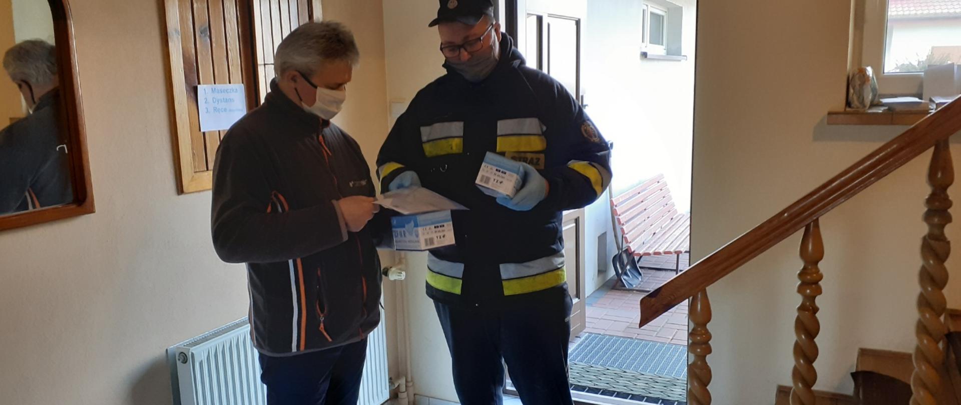 Zdjęcie przedstawia strażaka OSP Okup podczas przekazania maseczek proboszczowi Parafii w Okupie Wielkim