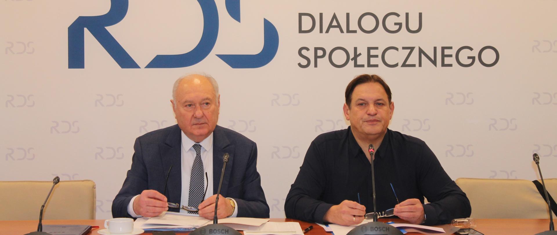 Na zdjęciu widnieje stół prezydialny za którym siedzą od lewej strony: Jan Klimek - Przewodniczący zespołu ds. rozwoju dialogu społecznego oraz Jacek Męcina – Przewodniczący zespołu ds. prawa pracy. W tle znajduje się baner z napisem Rada Dialogu Społecznego.