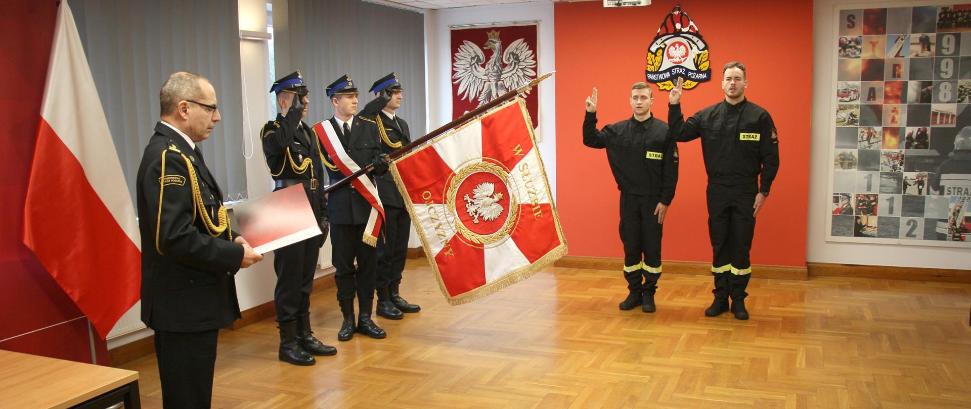 Dwóch strażaków składa ślubowanie przy sztandarze KM PSP w Lesznie