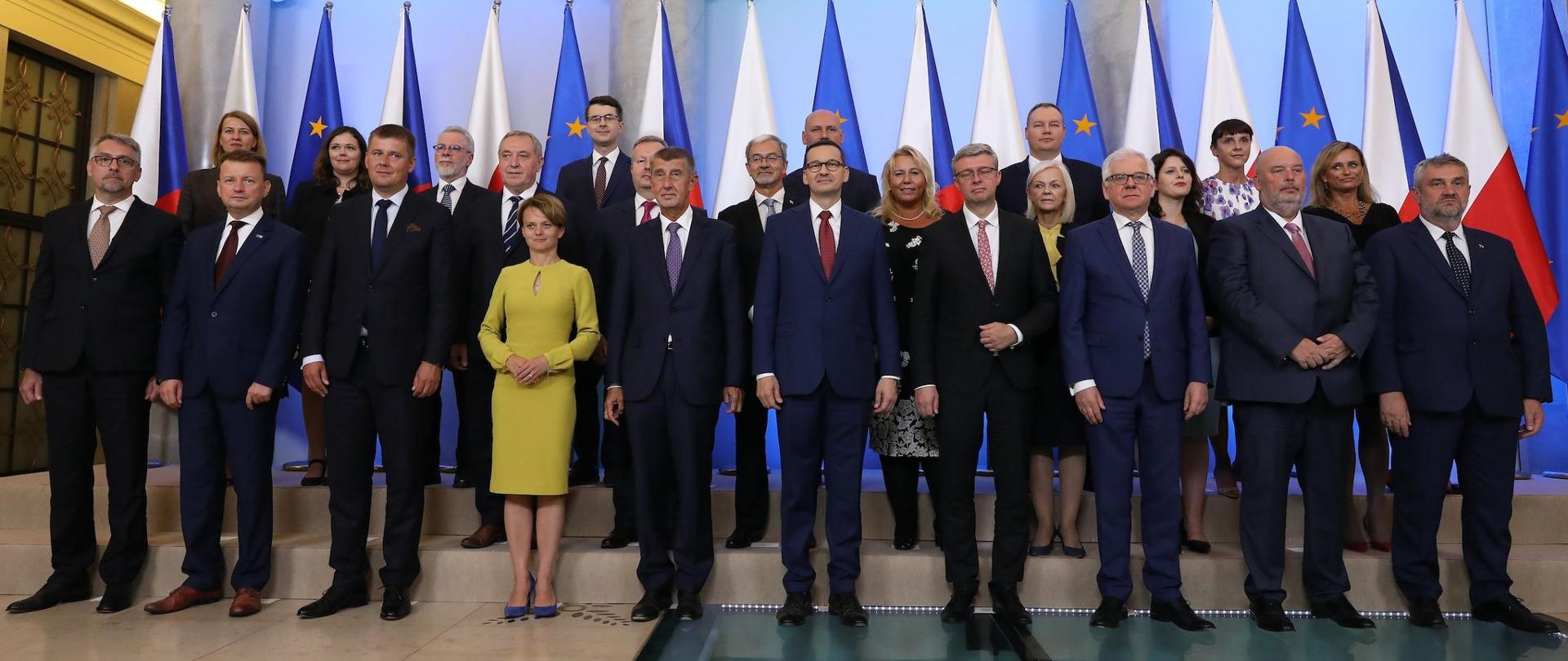 W sali na tle flag stoją w trzech rzędach uczestnicy polsko-czeskich konsultacji międzyrządowych
