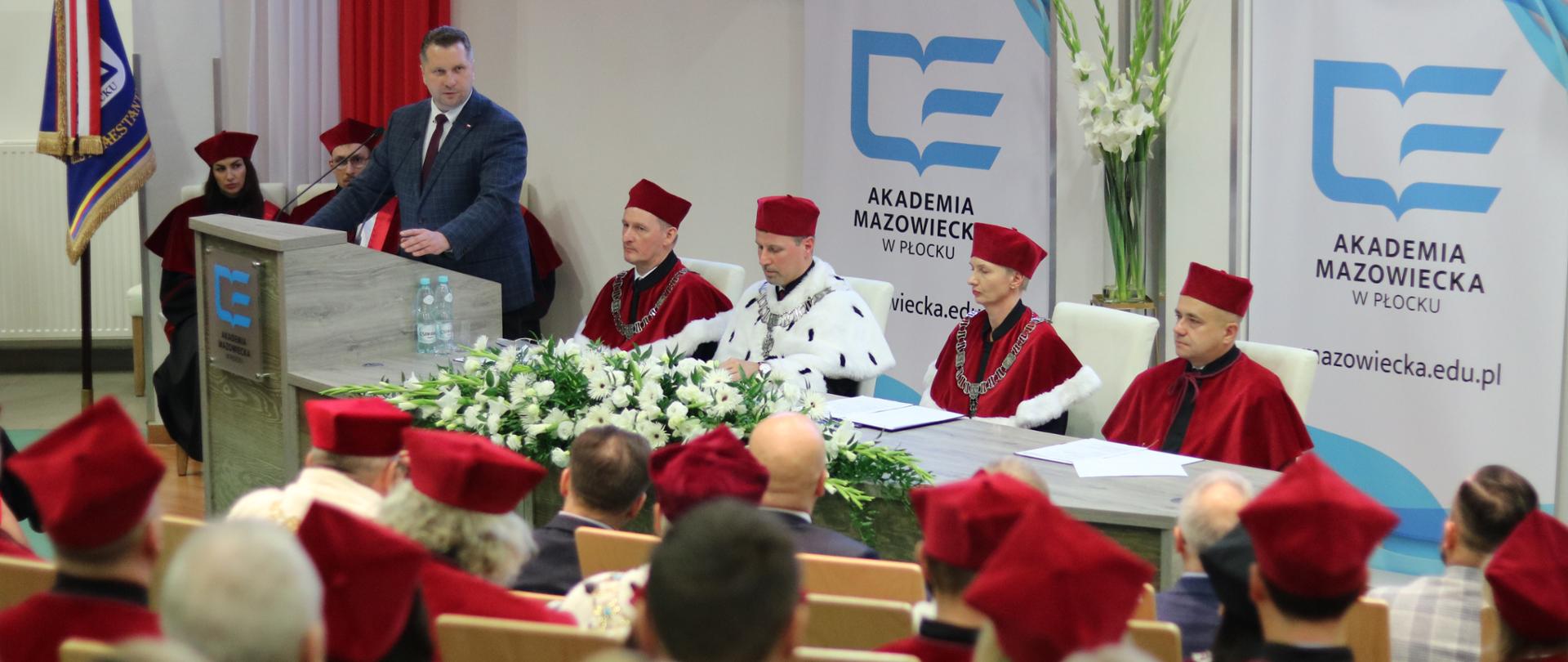 Minister Czarnek przy mikrofonie obok niego siedzą władze uczelni- kobieta i trzech mężczyzn, tyłem widać uczestników inauguracji