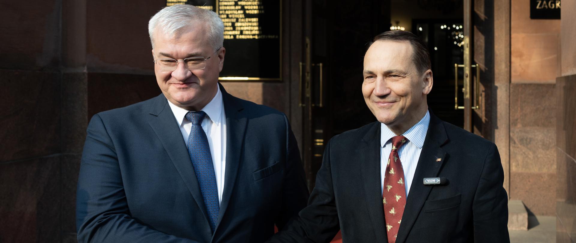 Na zdjęciu są ministrowie Spraw Zagranicznych Polski i Ukrainy. Są ubrani w garnitury. Za nimi jest budynek polskiego MSZ.