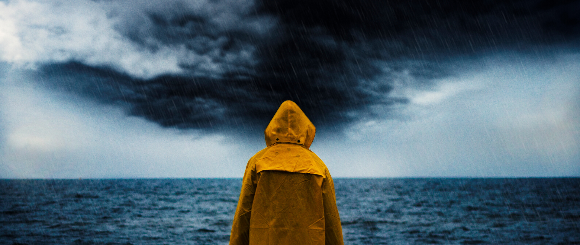 Chłopiec w żółtej kurtce patrzy na burzę nad morzem