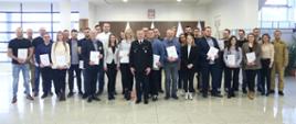 Grupowe zdjęcie uczestników szkolenia w towarzystwie Zastępcy Komendanta Centralnej Szkoły PSP, kobiety oraz dwóch funkcjonariuszy CS PSP
