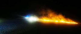 Zdjęcie przedstawia samochody pożarnicze gaszące pożar ścierniska.