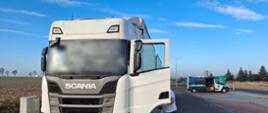 Ciężarówka marki Scania zatrzymana do kontroli drogowej, z otwartymi drzwiami kabiny, w tle pojazd Inspekcji Transportu Drogowego