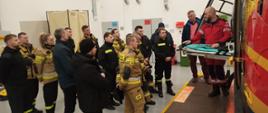 Szkolenie z zakresu współdziałania z LRP - na zdjęciu strażacy w ubraniu koszarowym i specjalnym zwiedzają budynek LPR i patrzą na śmigłowiec,