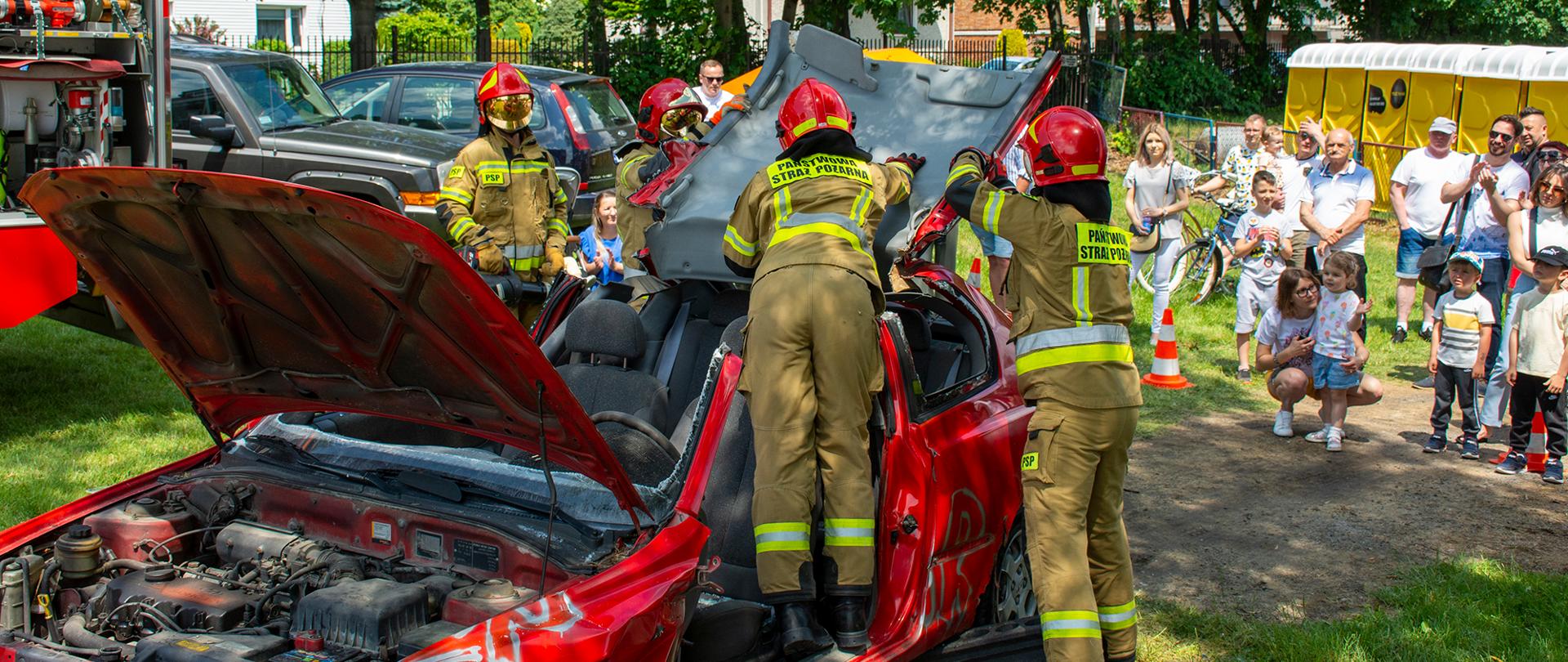 Na zdjęciu widoczni strazacy którzy rozcinaja i rozginają dach w pojeździe