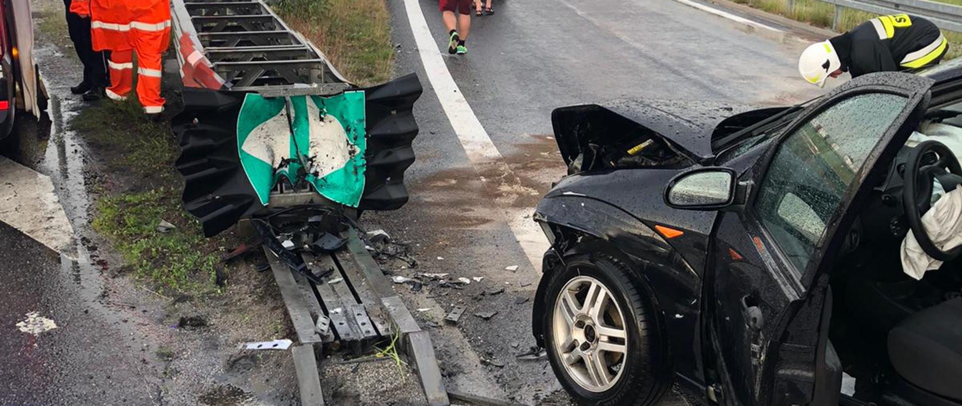 Widoczne miejsce zdarzenia uszkodzony pojazd, uszkodzoną barierę energochłonna oraz służby działające na miejscu.
