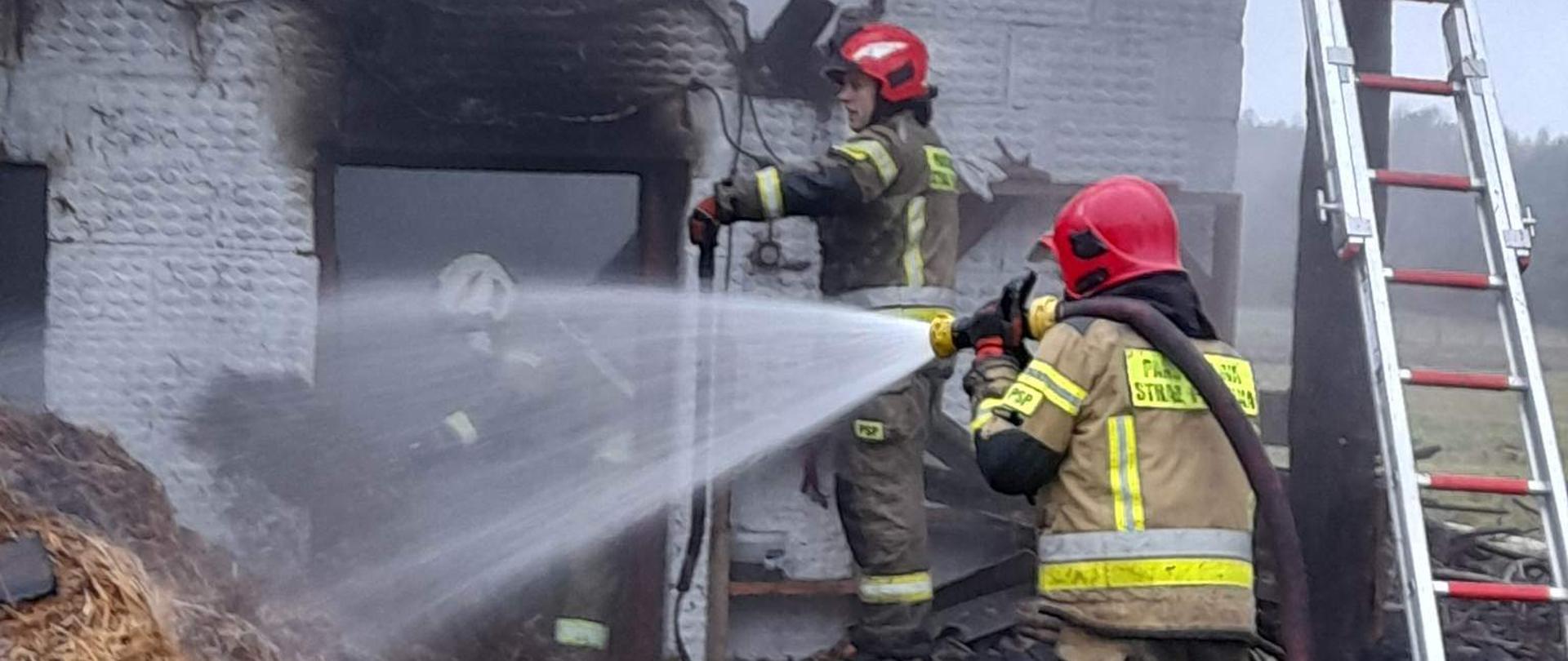 Na zdjęciu palący się budynek i strażacy.