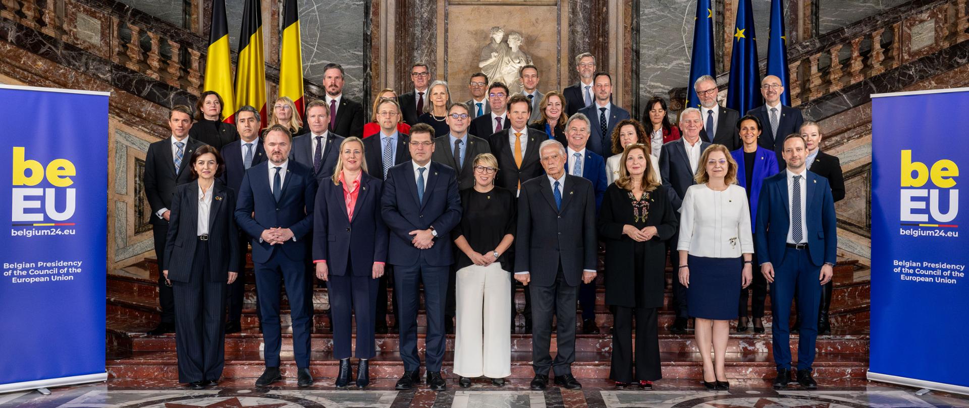 Grupa około 30 osób z przewagą mężczyzn pozuje do oficjalnego zdjęcia na marmurowych schodach